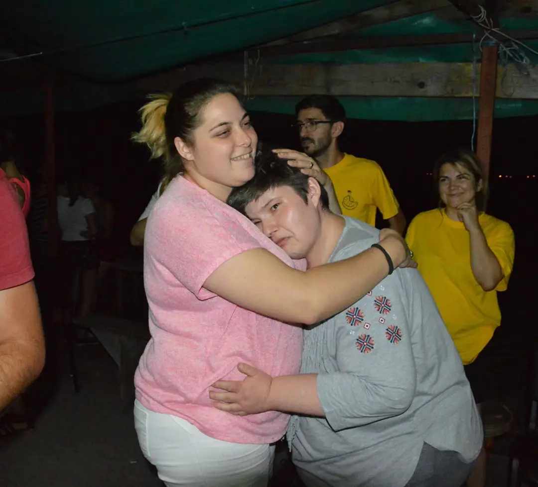 Două participante se îmbrățișează la o seară de tabără